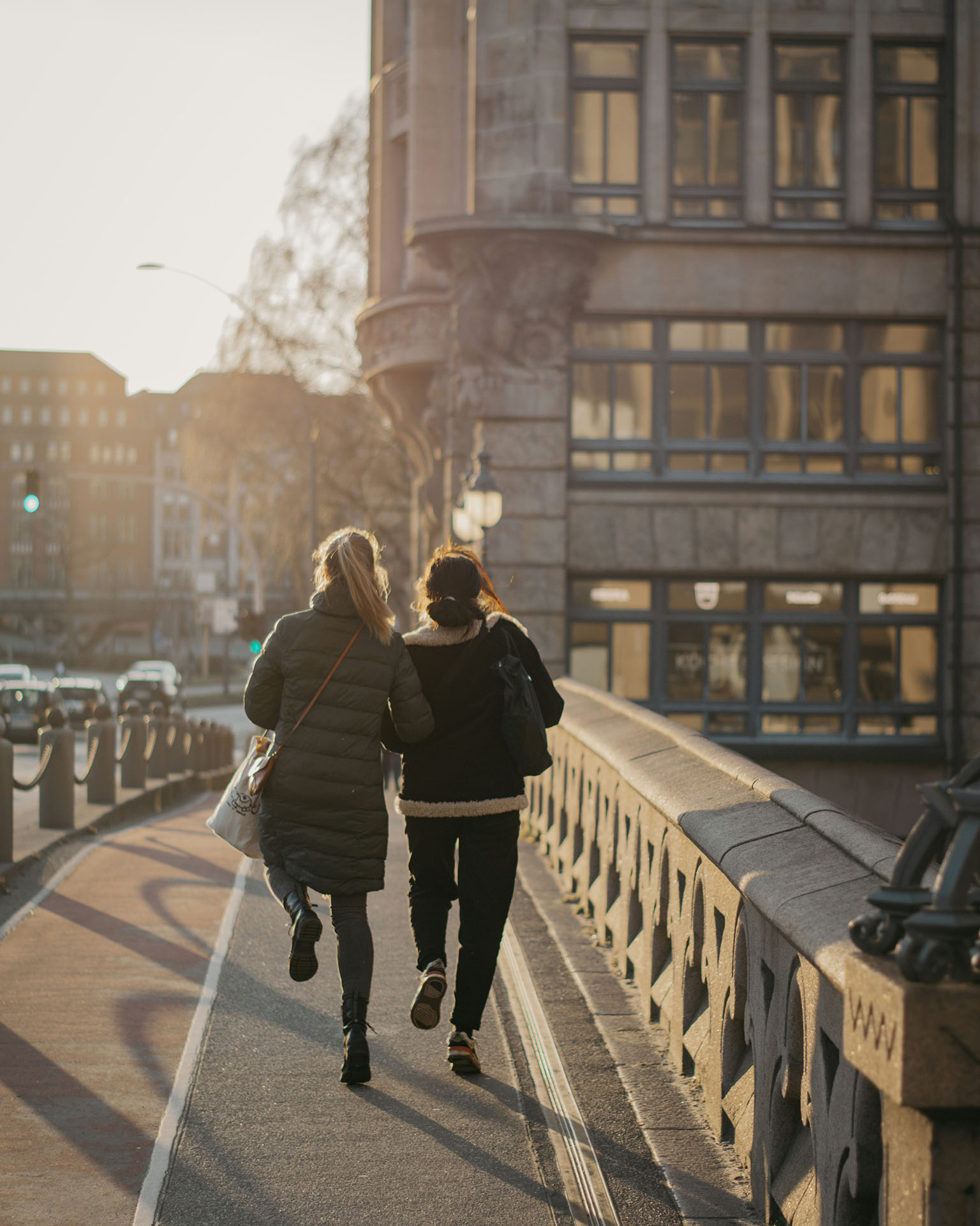 Zwei Personen gehen bei Sonnenuntergang auf einer Brücke entlang.